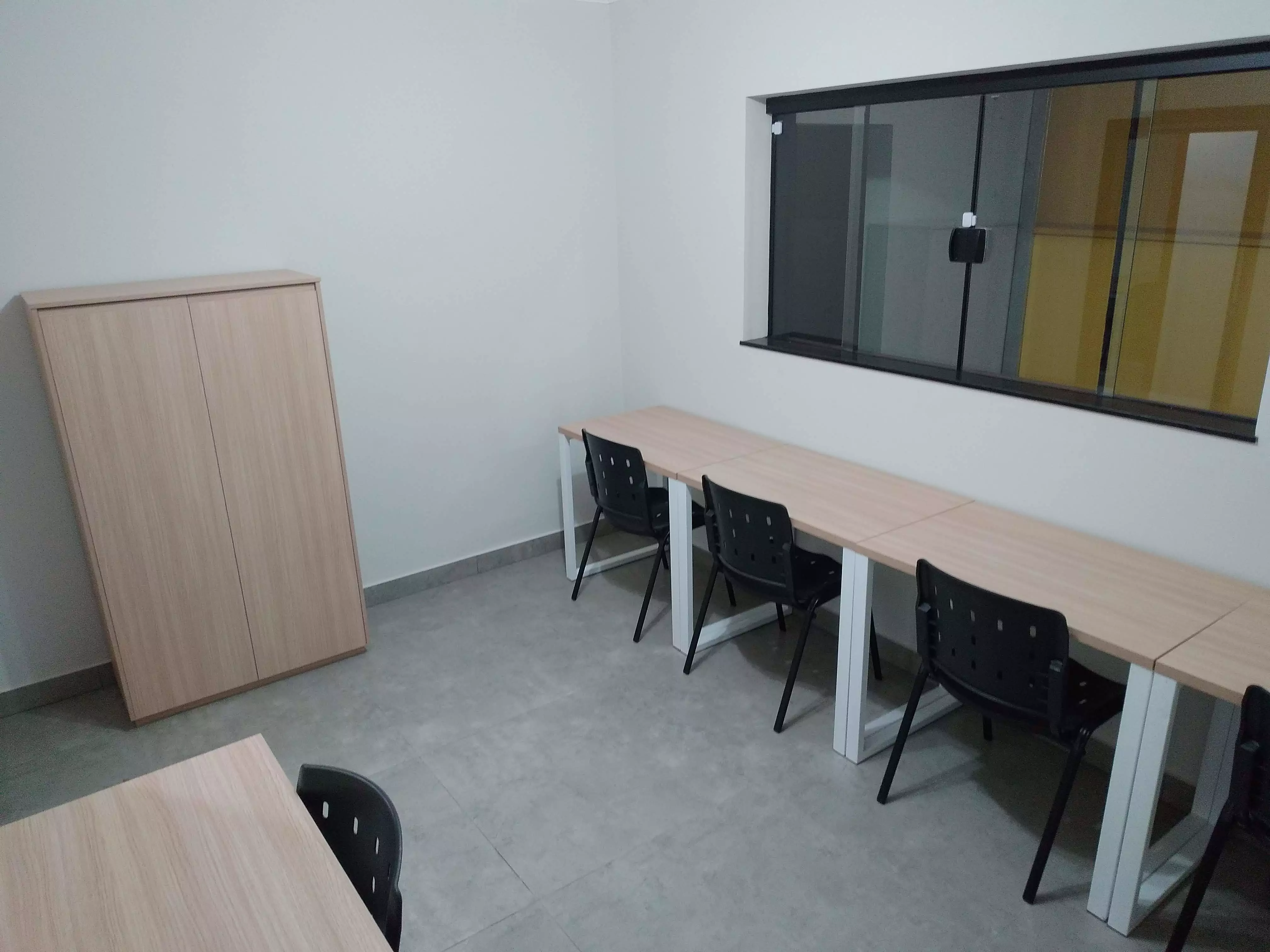 imagem da sala de reunião, com seis cadeiras, uma mesa e uma televisão no Coworking