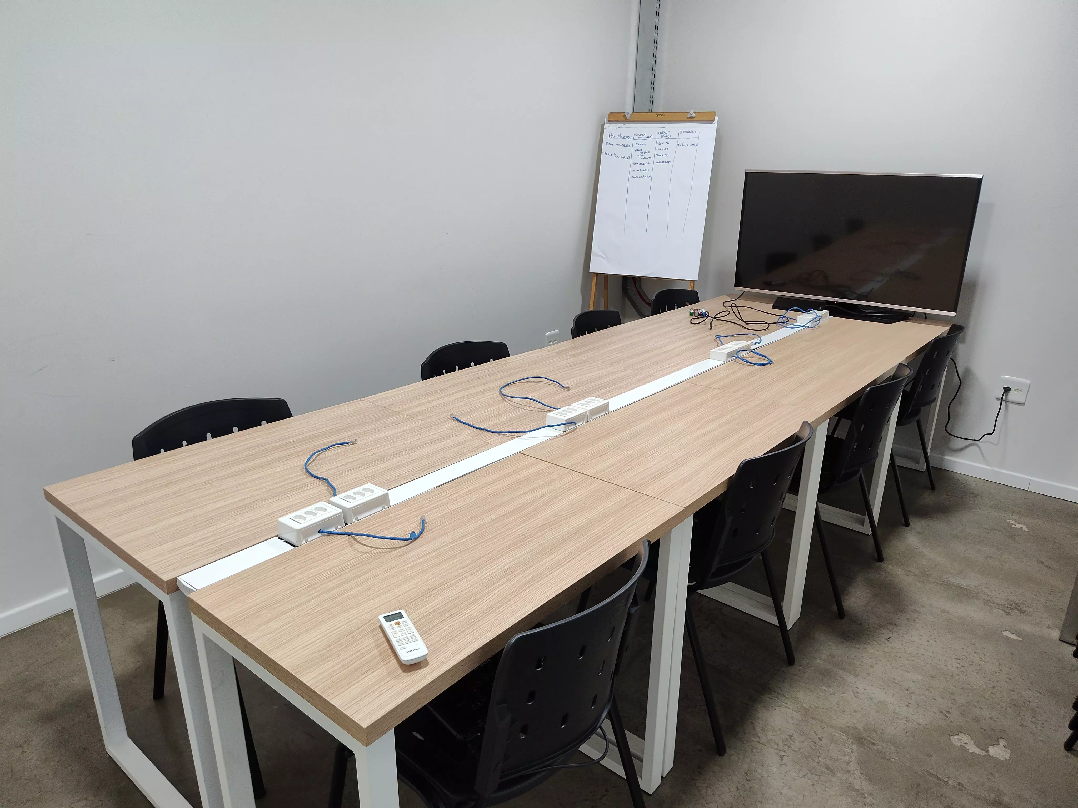 imagem da sala de reunião, com seis cadeiras, uma mesa e uma televisão no Coworking